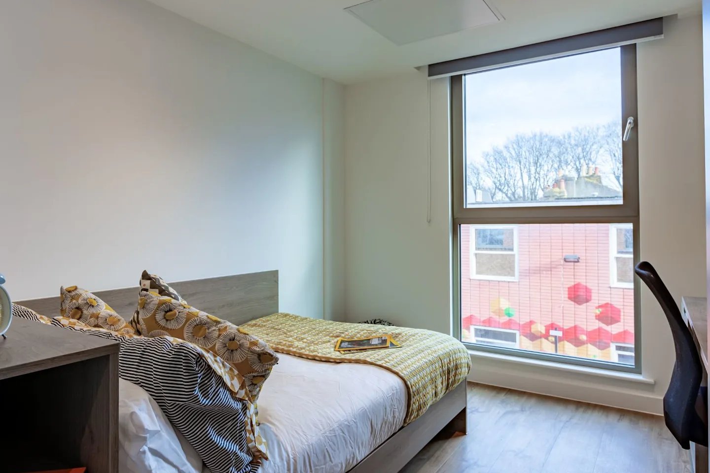 Bed with patterned pillows and desk Bedroom at Pavilion Point in Brighton Student Accommodation