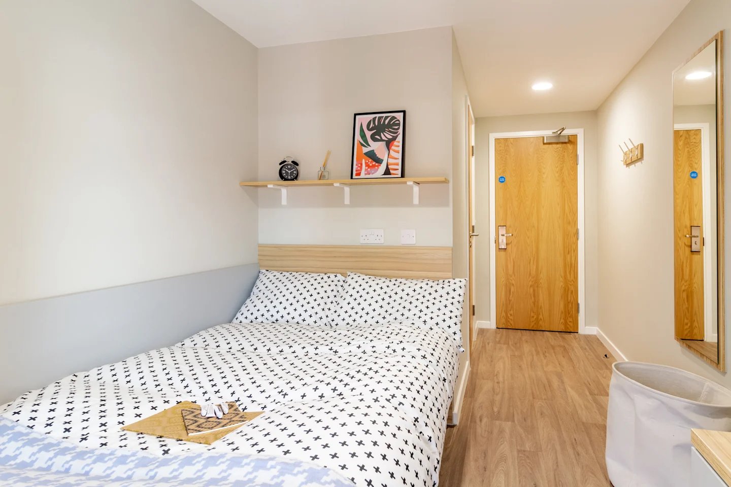 Bed with patterned bedding clock shelf doorway mirror bedroom at Gulson Gardens in Coventry Student Accommodation