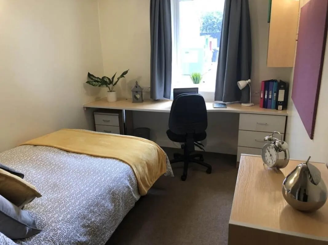 Bed desk chair and alarm clock Bedroom at Horton House Bradford in Bradford Student Accommodation