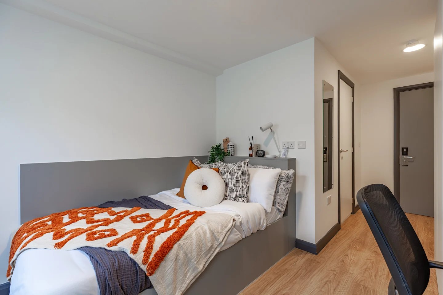 Bed with orange throw pillows and patterned bedding bedroom at Winfield Court in Nottingham Student Accommodation