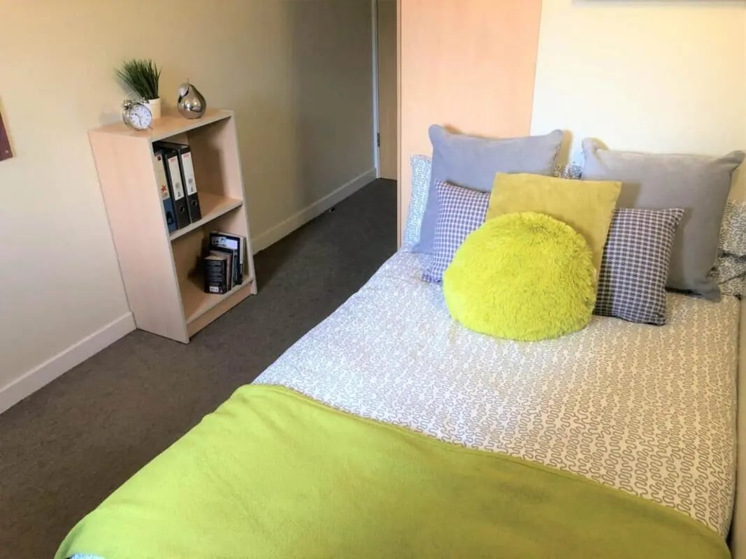 Bed with pillows books and alarm clock bedroom at Horton House Bradford in Bradford Student Accommodation