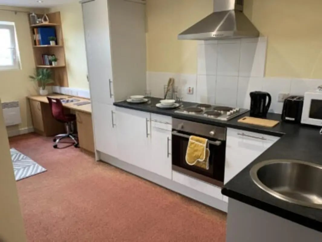 Desk with chair, kitchen appliances, and cabinets kitchen at Longside House Bradford in Bradford Student Accommodation