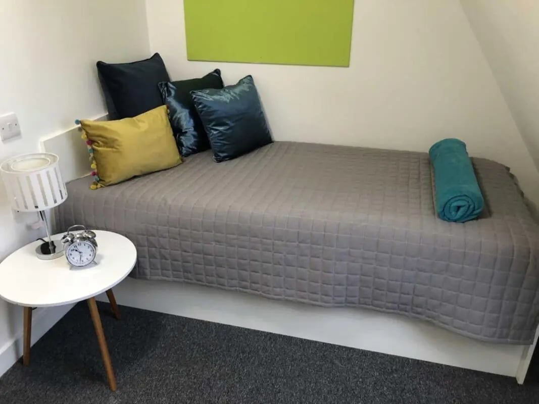 Bed alarm clock lamp pillows and rolled towel bedroom at Tudor Studios in Leicester Student Accommodation