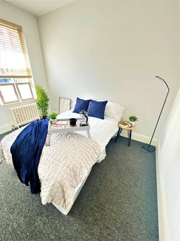 Bed with tray books and pillows bedroom at Highgate in Leicester Student Accommodation