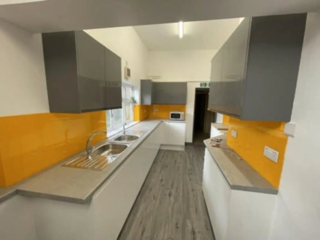 Modern grey cabinets orange backsplash stainless steel sink kitchen at Highgate in Leicester Student Accommodation