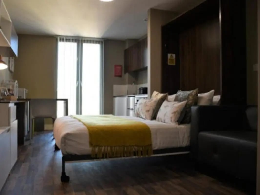 Bed with yellow throw and sofa bedroom at Pembroke Studios in Liverpool Student Accommodation