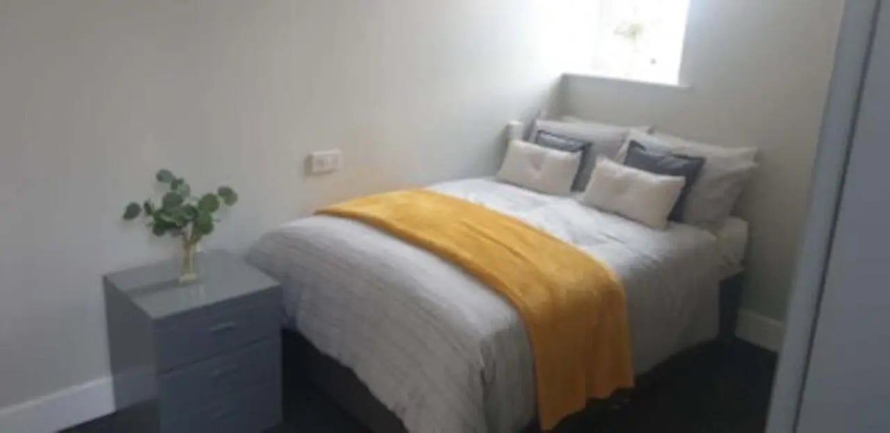 Bed with yellow throw pillows and plant bedroom at St Mary's Newcastle in Newcastle Upon Tyne Student Accommodation