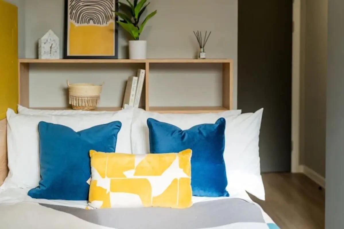 Bed with blue pillows and shelf Bedroom at Zinc Quarter in Bristol Student Accommodation