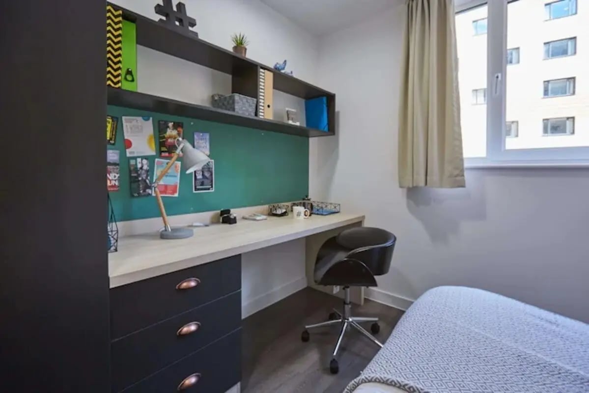 Desk chair bulletin board and bed student accommodation study area at Mannequin House in London Student Accommodation