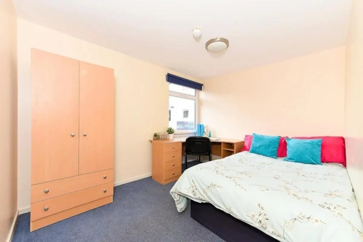 Wardrobe desk bed with teal pillows bedroom at Queens Court Leicester in Leicester Student Accommodation