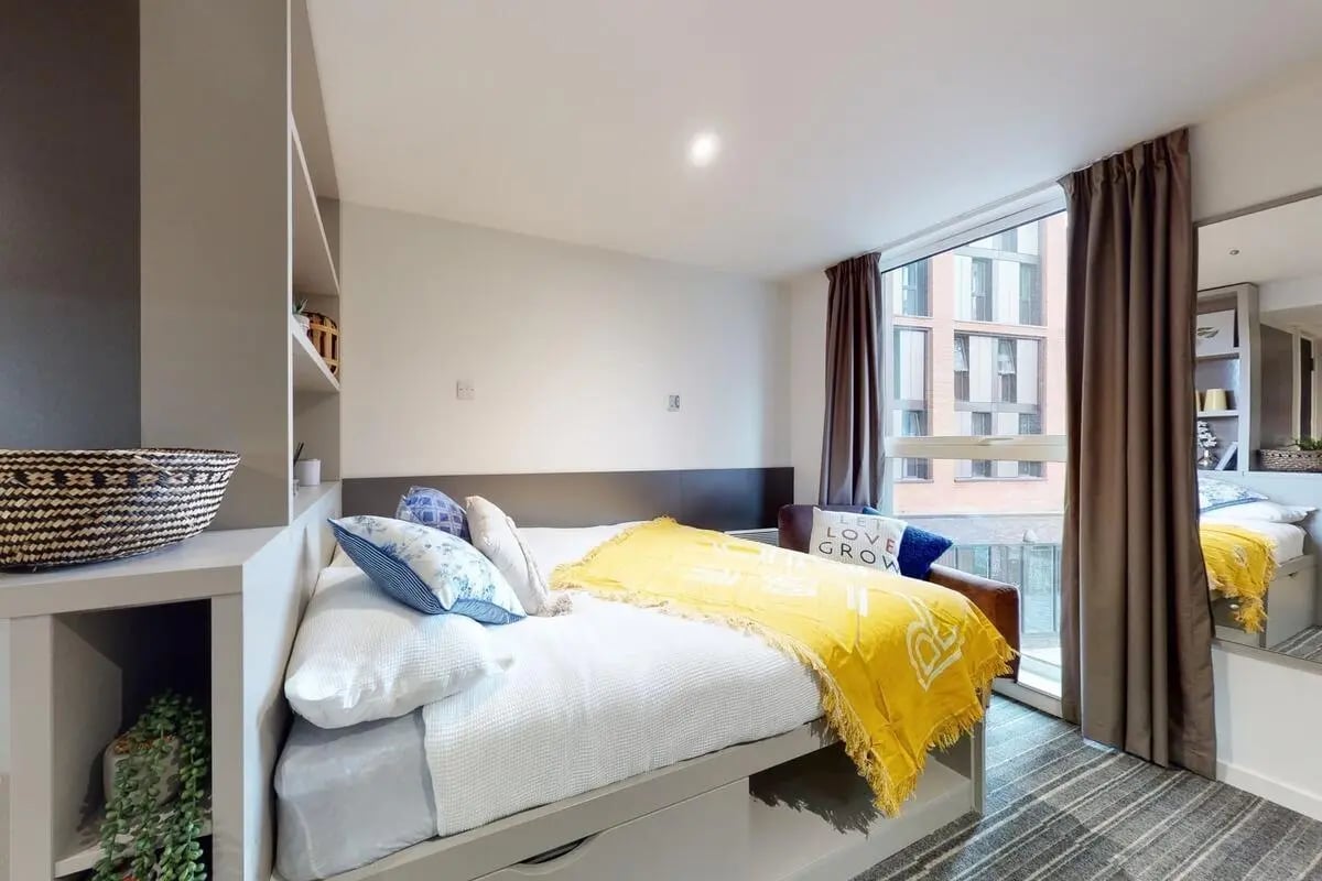 Bed with yellow throw and pillows bedroom at Canvas Coventry City Point in Coventry Student Accommodation