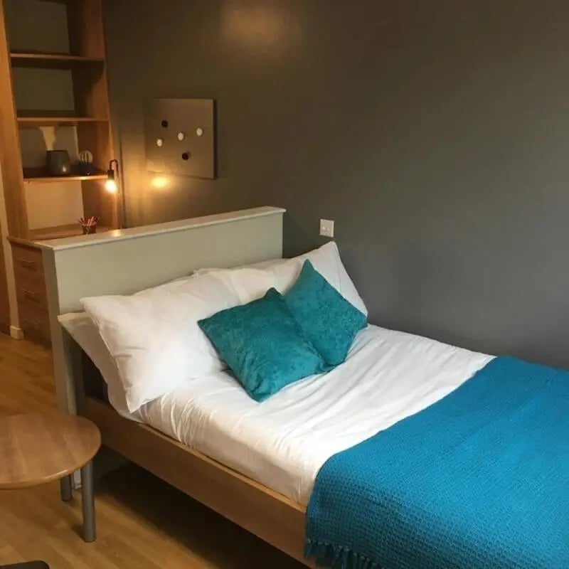 Bed with blue throw and pillows bedroom at Lady Nicolson Court in Edinburgh Student Accommodation