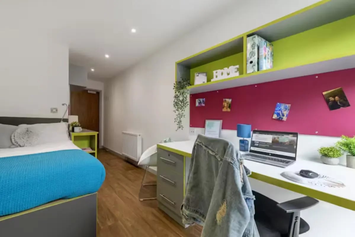 Bed desk with laptop and pink noticeboard bedroom at The Boulevard in York Student Accommodation