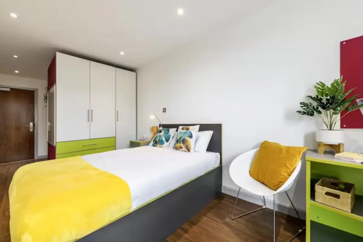 Bed with yellow blanket and chair bedroom at The Boulevard in York Student Accommodation
