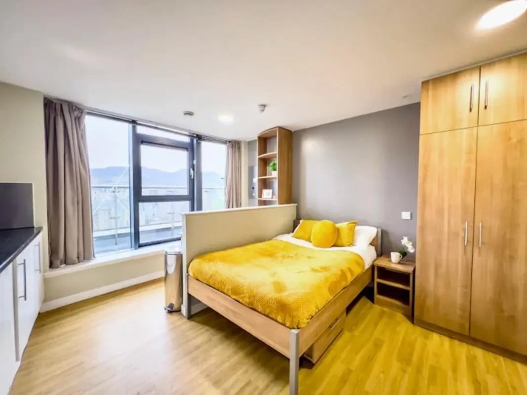 Bed with yellow bedding and wardrobe bedroom at Lady Nicolson Court in Edinburgh Student Accommodation