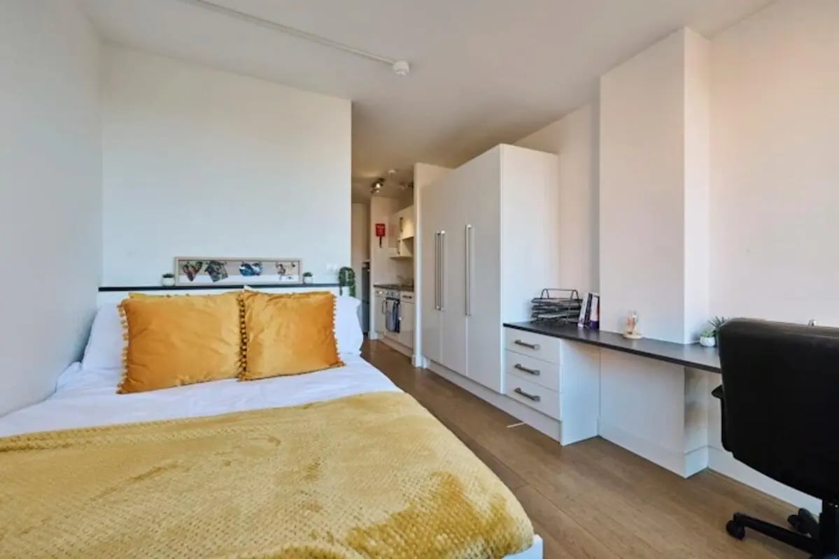 Bed with yellow pillows and desk study area at Upperton Road in Leicester Student Accommodation