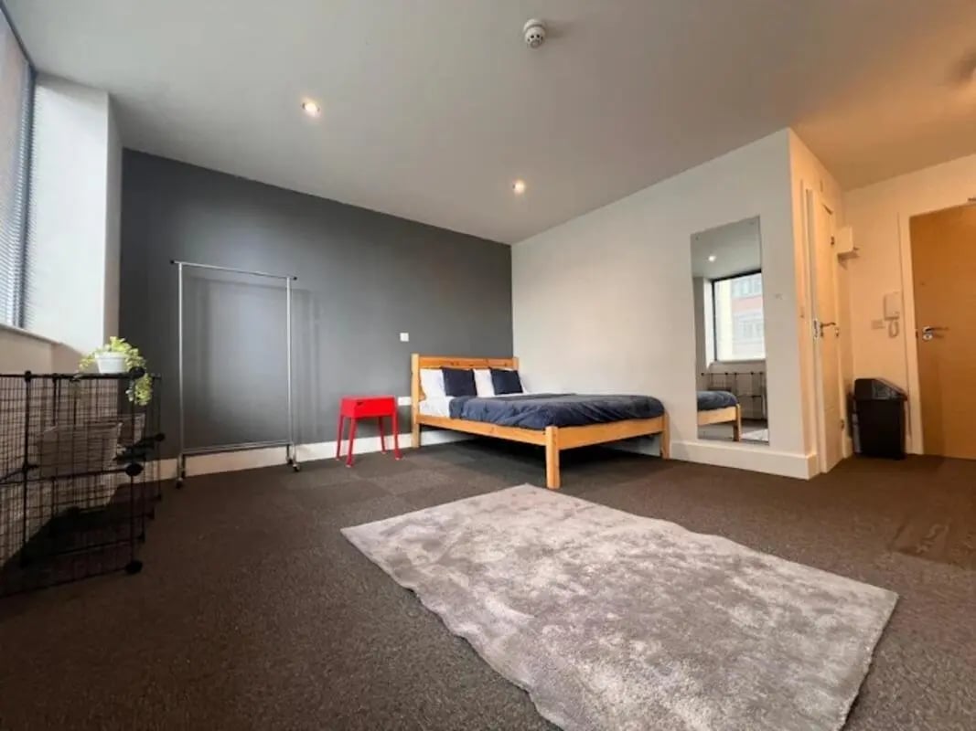 Bed black rack red stool grey rug bedroom at Hydrogen in Nottingham Student Accommodation