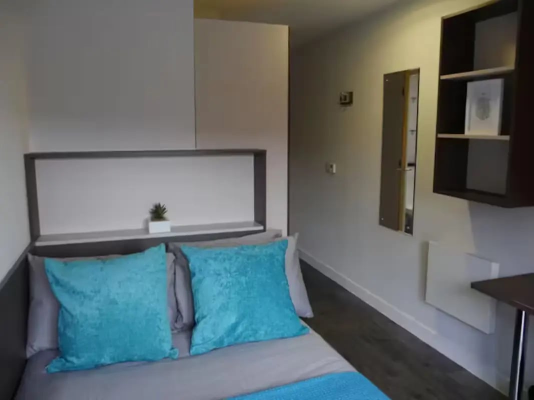 Bed with blue pillows and shelf bedroom at Cornerhouse in Sheffield Student Accommodation