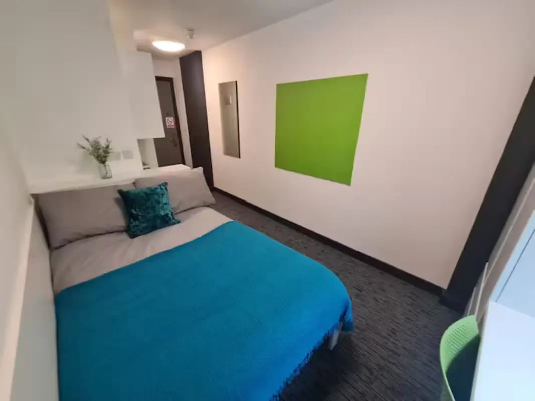 Bed with blue blanket and green pillow bedroom at St James Point in Newcastle Upon Tyne Student Accommodation