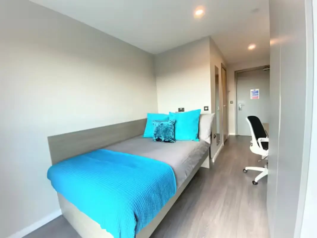 Bed with blue throws and pillows desk and chair bedroom at Little Patrick Street in Belfast Student Accommodation