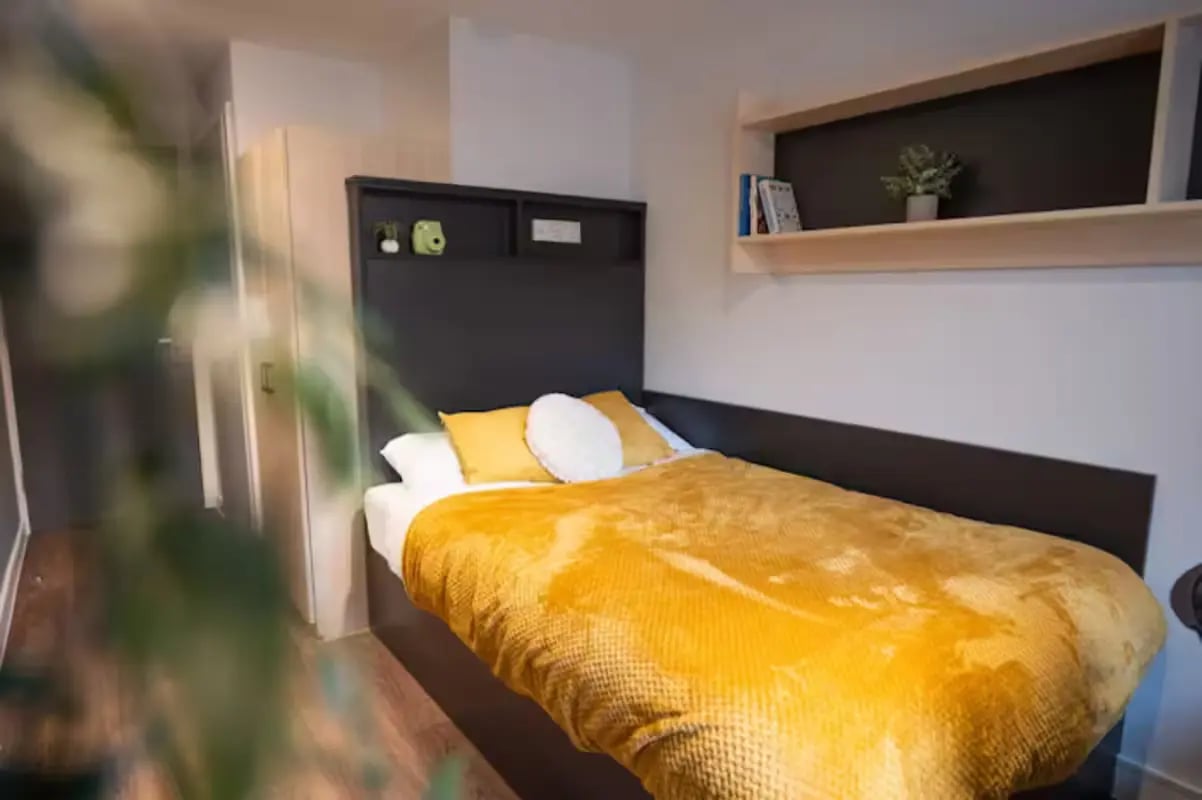 Bed with yellow bedding and shelf Bedroom at Portsburgh Court in Edinburgh Student Accommodation