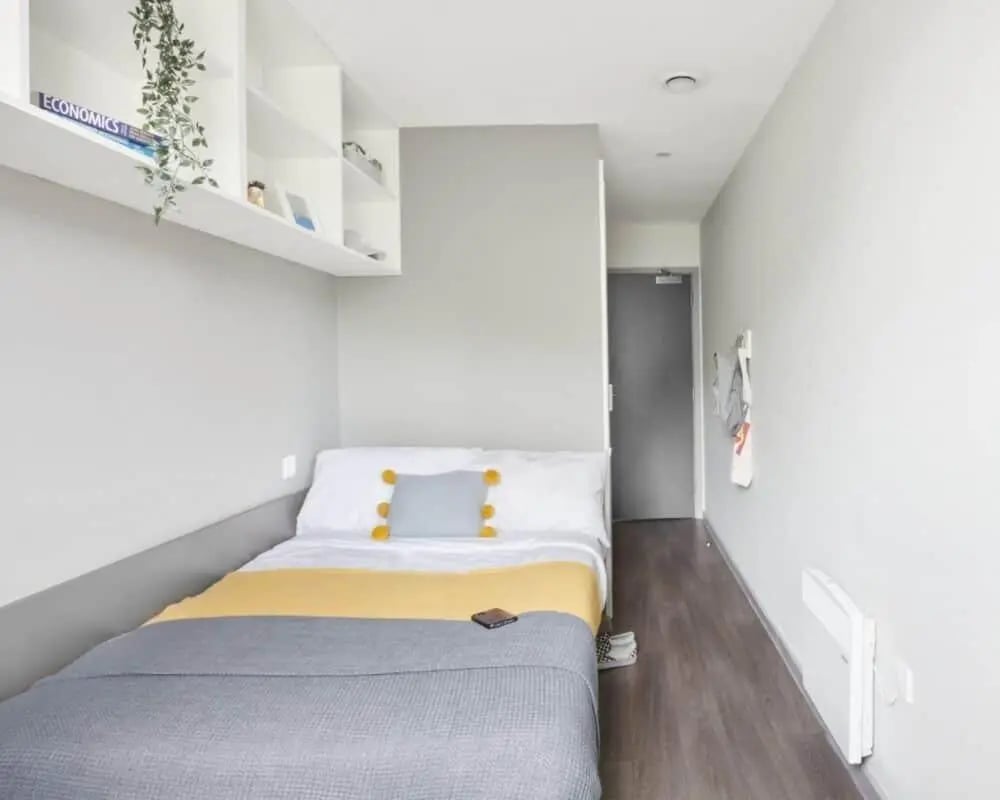 Bed with grey and yellow blanket shelves bedroom at Gosford Gate in Coventry Student Accommodation