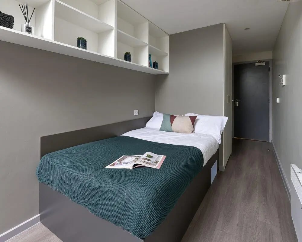 Bed with teal blanket and open book bedroom at Gosford Gate in Coventry Student Accommodation
