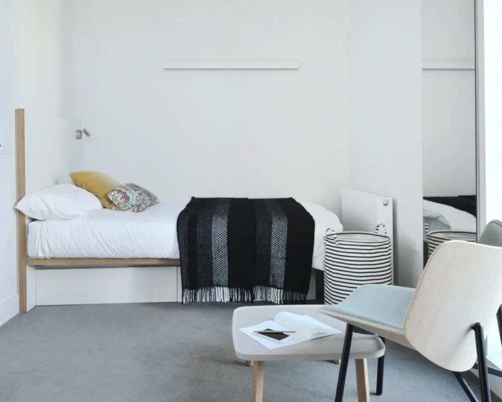 Bed pillows blanket basket chair table bedroom at Victoria Hall Kings Cross in London Student Accommodation
