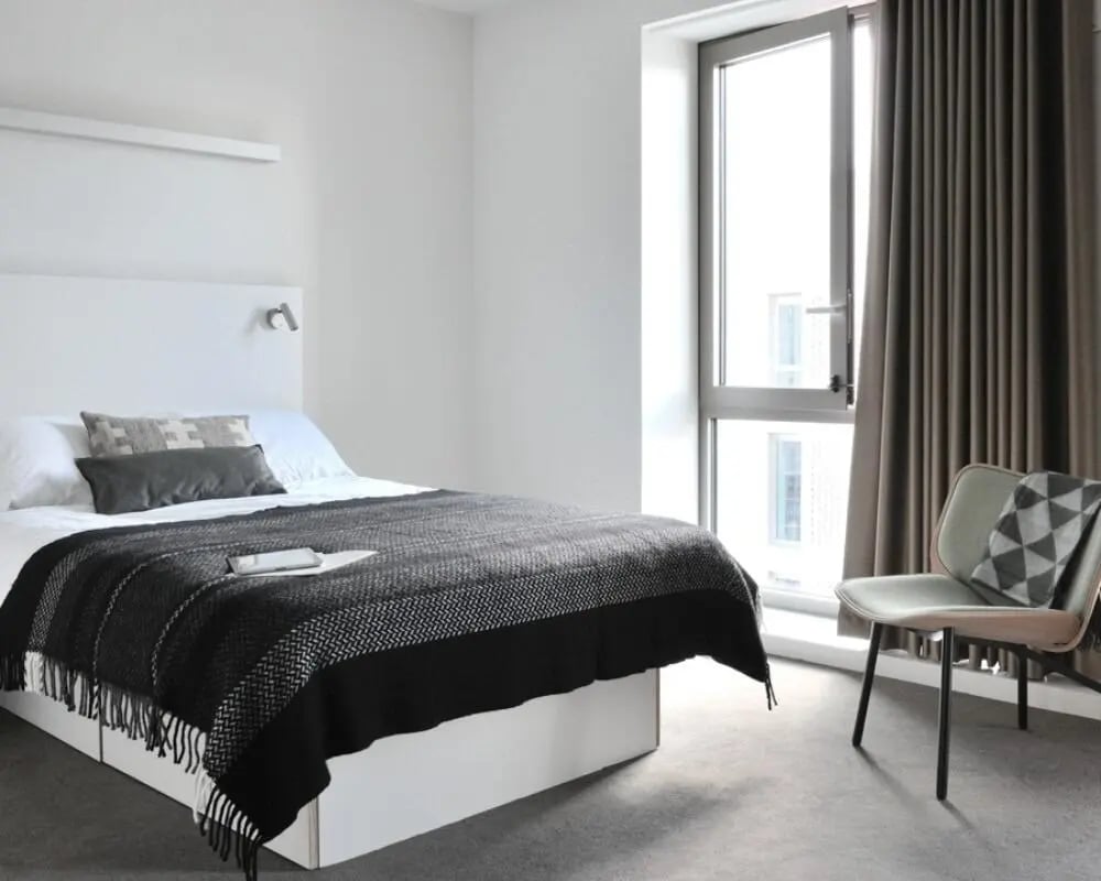 Bed with blanket pillows chair window Bedroom at Victoria Hall Kings Cross in London Student Accommodation