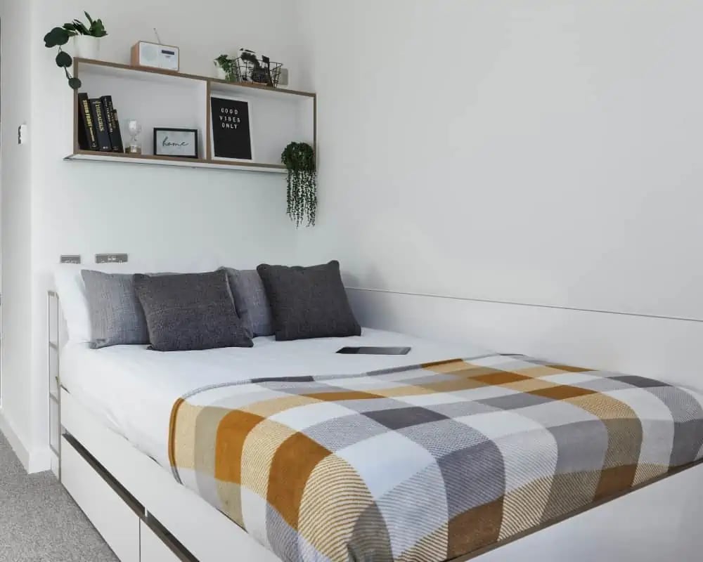Bed with plaid blanket pillows shelf bedroom at 41 Castle Street in Leicester Student Accommodation
