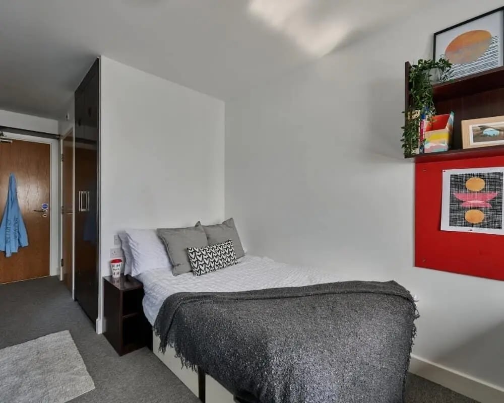 Bed with grey blanket and pillows small cabinet Bedroom at Heantun Point in Wolverhampton Student Accommodation