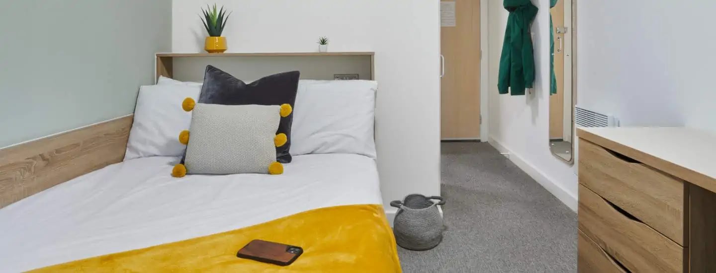 Bed with pillows and yellow throw bedroom at Sky Blue Point in Coventry Student Accommodation