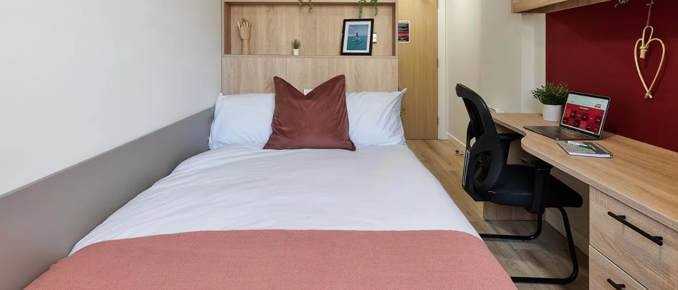 Bed with pillows and desk with laptop bedroom at Christchurch Road in Bournemouth Student Accommodation