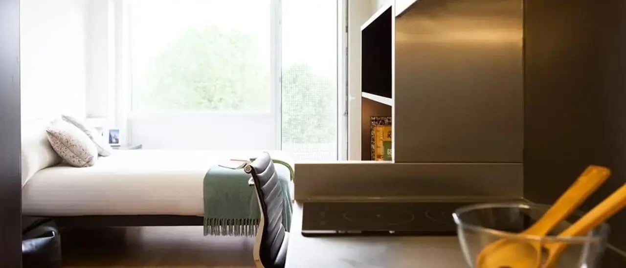 Bed pillows throw blanket and cooktop kitchen at Chapter Portobello in London Student Accommodation