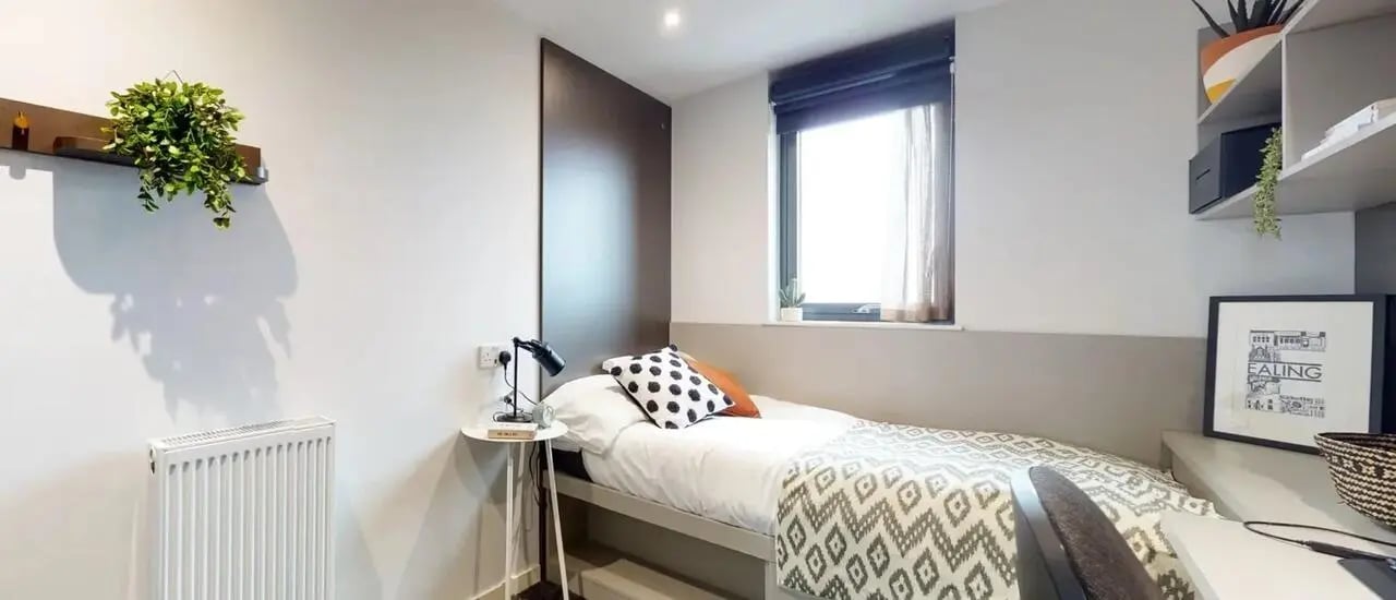 Bed with patterned blanket side table lamp and window bedroom at Chapter Ealing in London Student Accommodation