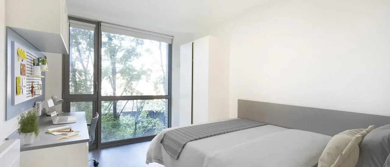 Bed desk and closet with large window bedroom at Chapter Lewisham in London Student Accommodation
