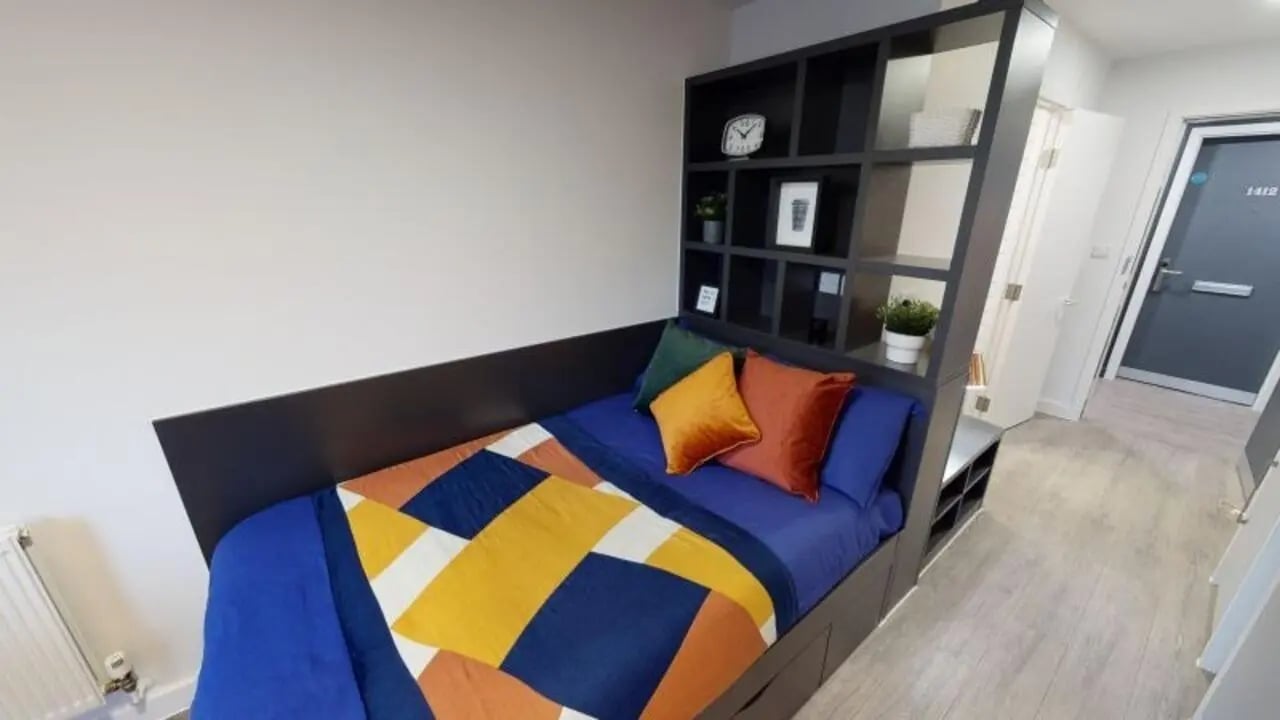 Bed with shelving unit and hallway bedroom at iQ Shoreditch in London Student Accommodation