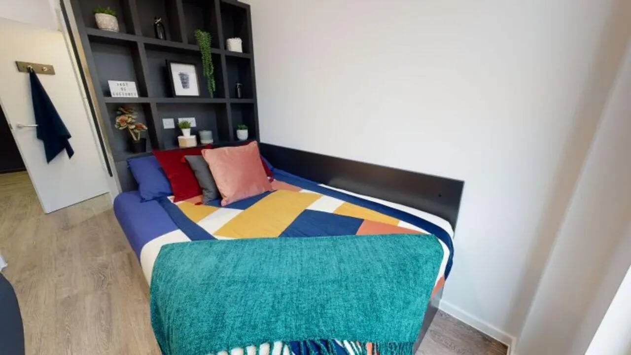 Bed with colorful bedding shelves above bedroom at iQ Bloomsbury in London Student Accommodation