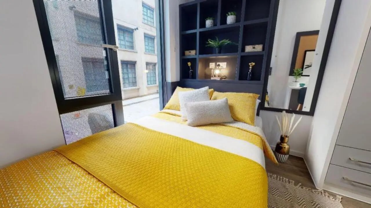 Yellow bed with pillows shelves mirror Bedroom at iQ Bloomsbury in London Student Accommodation