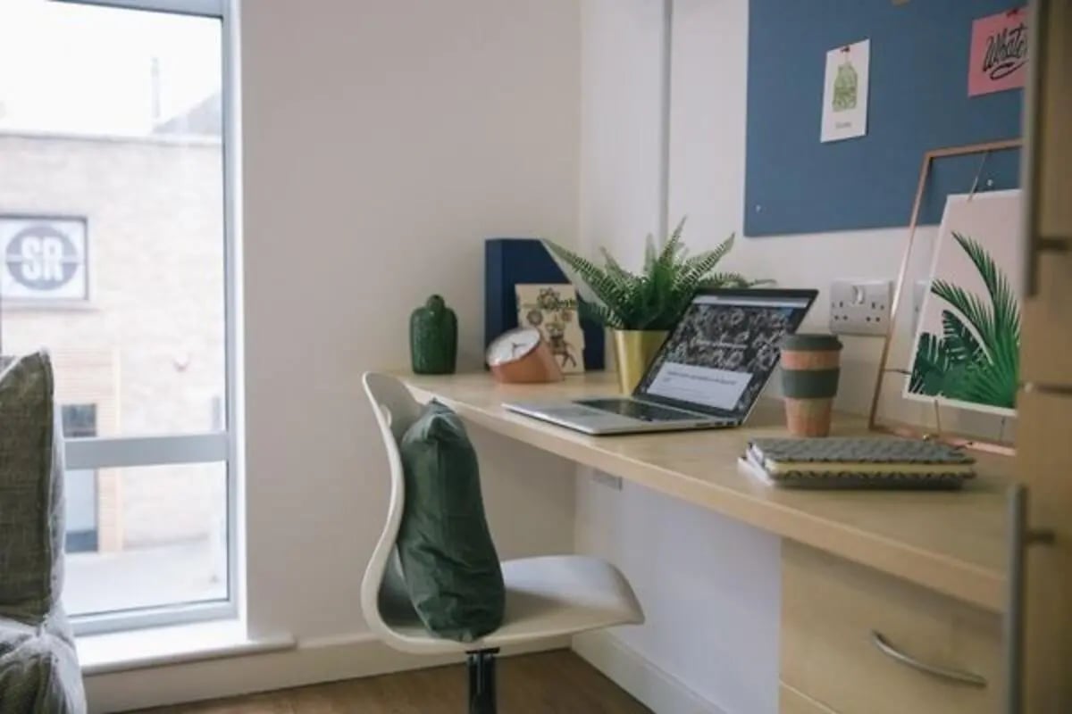 Desk with laptop plant and coffee cup study area at Victoria Point in Manchester Student Accommodation