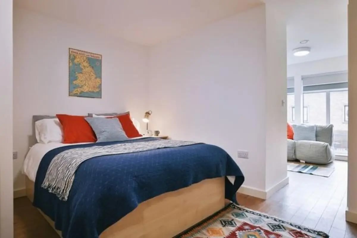 Bed with red pillows map and rug bedroom at Dean Clarke Lofts in Exeter Student Accommodation
