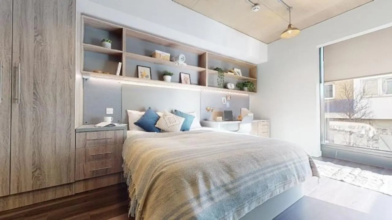 Bed desk shelves wardrobe and window bedroom at iQ Aldgate in London Student Accommodation