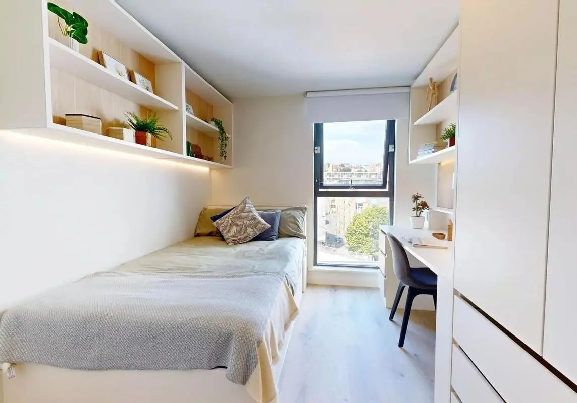 Bed desk shelves plants and city view bedroom at iQ Bristol in Bristol Student Accommodation