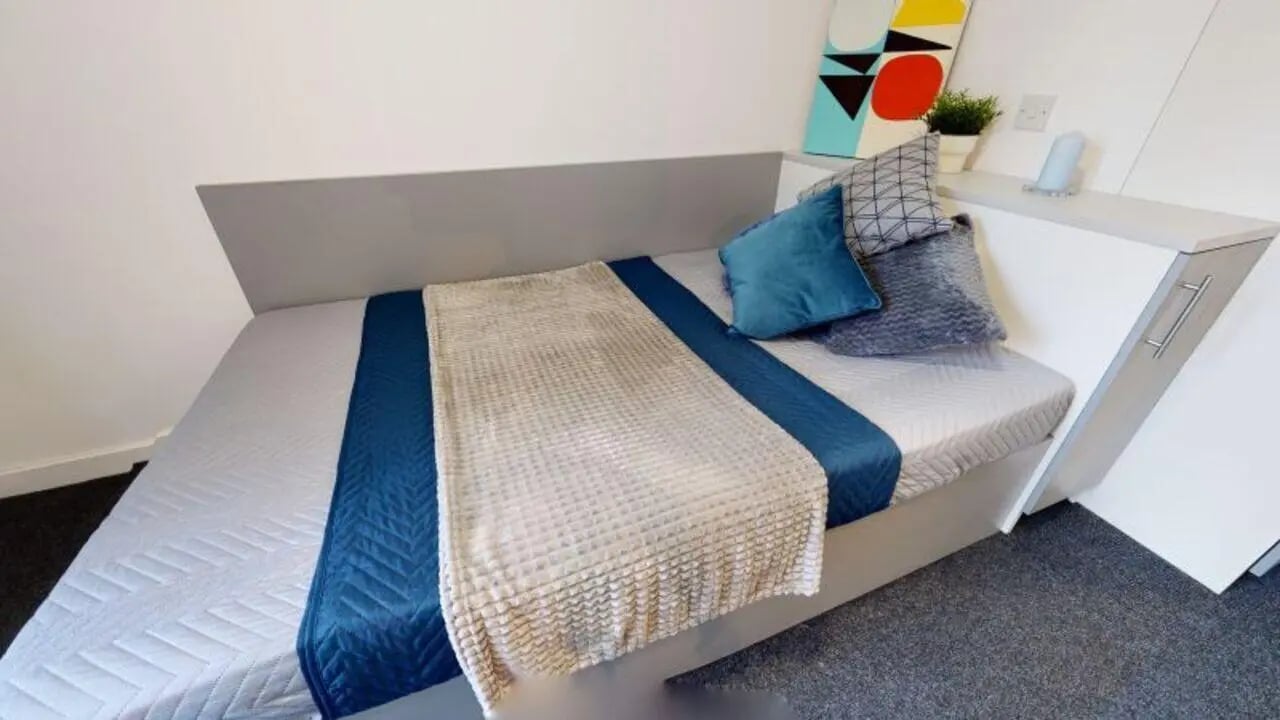 Bed with blue and cream blankets two pillows bedroom at iQ Century Square in Sheffield Student Accommodation