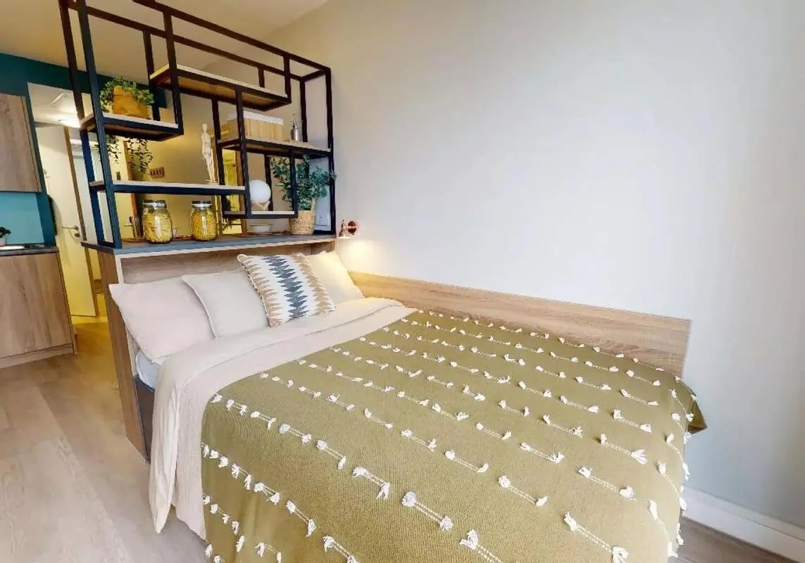 Bed with shelves and kitchen view bedroom at iQ Bankside in London Student Accommodation