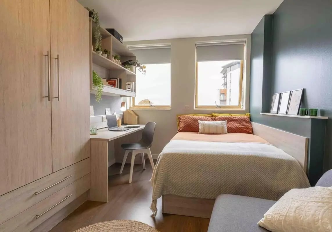 Bed desk shelves wardrobe and chairs bedroom at iQ Kingston in Kingston Upon Thames Student Accommodation