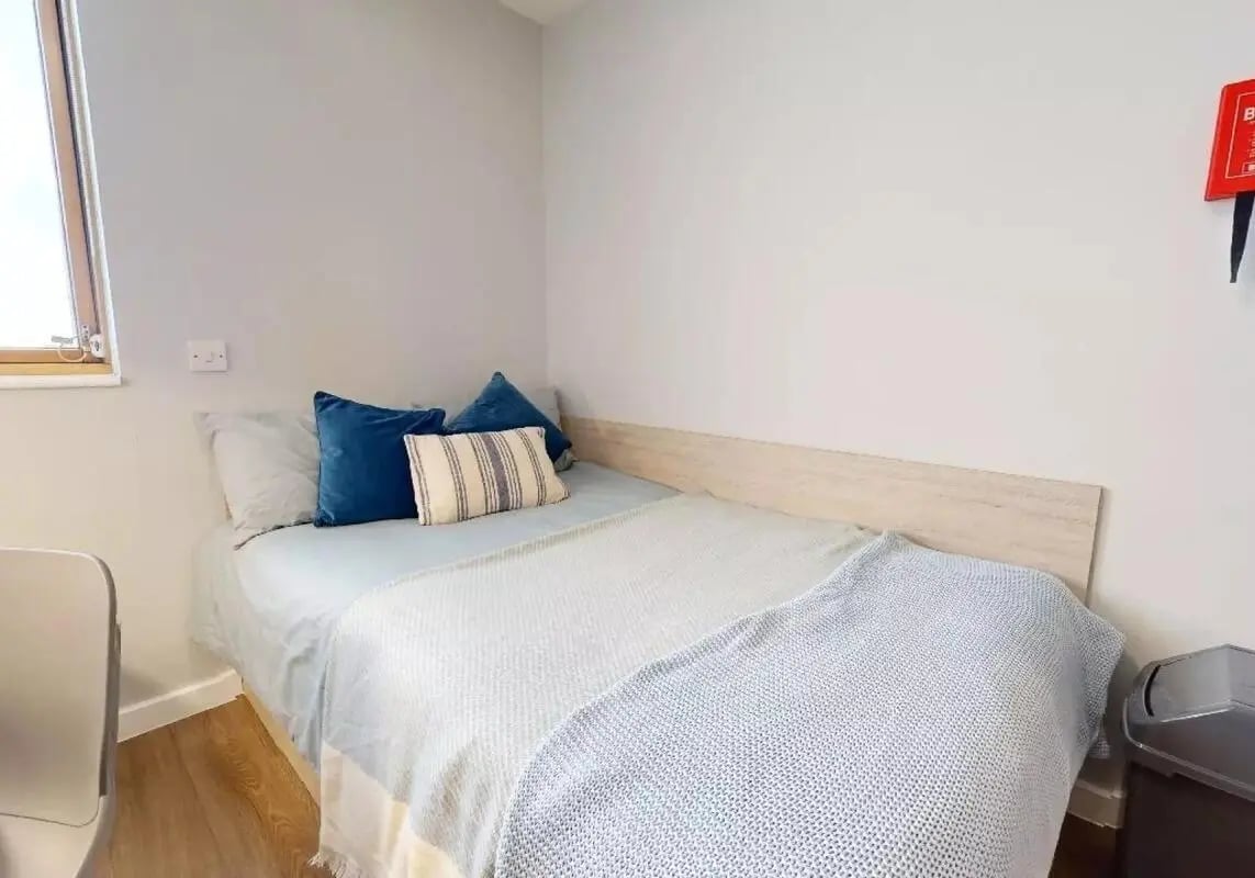 Bed with blue pillows and light blanket bedroom at iQ Kingston in Kingston Upon Thames Student Accommodation