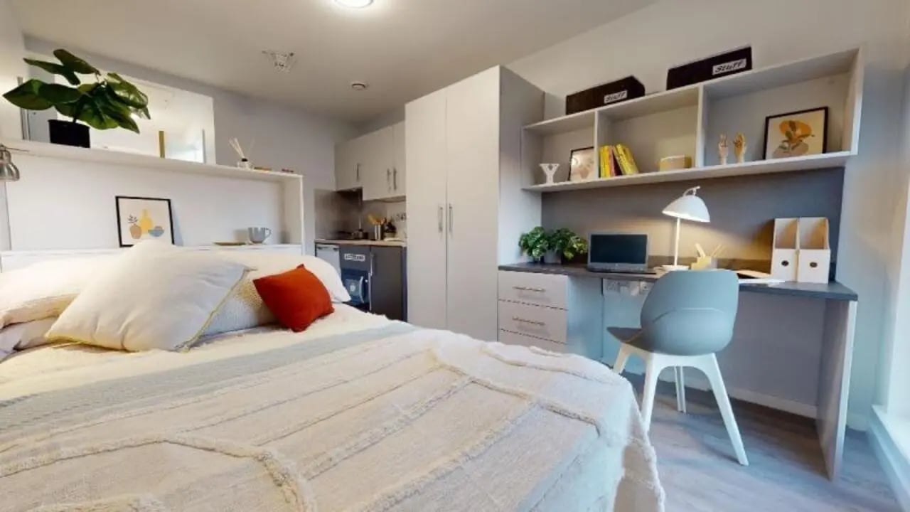 Bed desk and kitchen area bedroom at iQ City in London Student Accommodation