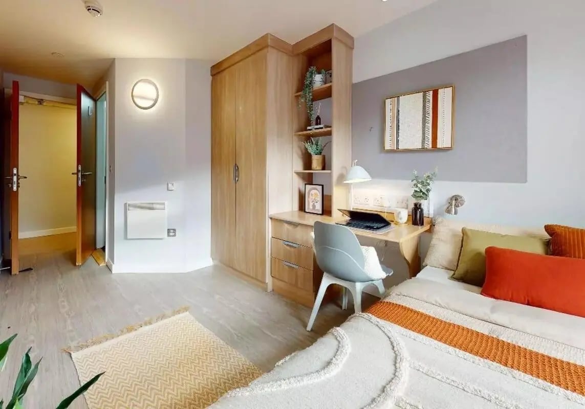 Wardrobe desk chair bed with colorful pillows bedroom at iQ Steel in Sheffield Student Accommodation