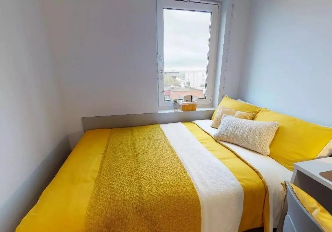 Bed with yellow bedding and pillows bedroom at iQ Broderick House in Birmingham Student Accommodation